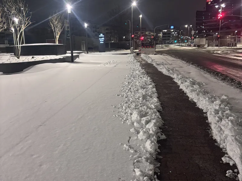 Geräumter Gehweg neben schneebedeckter Fläche